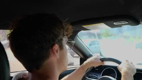 Young man feeling comfortable while sitting on driver seat in his car. Back view Stock Photos