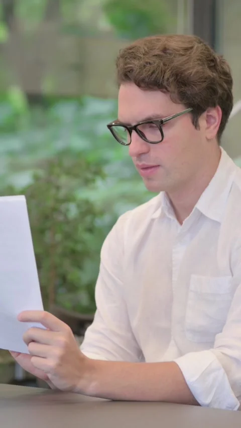 Young Man Feeling Happy while Reading Documents in Modern Office, Vertical Video Stock Footage 340032729