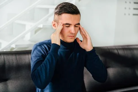 Young man feeling headache, keeps his hands on temples Stock Photos