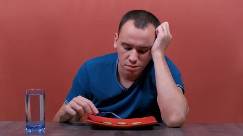 Young man feeling sad and bored with diet not wanting to eat vegetables  Stock Footage 123017853