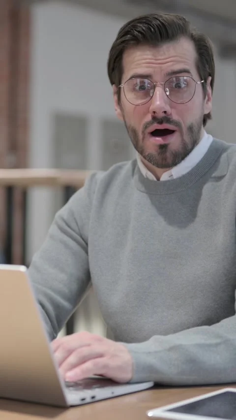 Young Man feeling Shocked while using Laptop in Office, Vertical Video Stockbeeldmateriaal 339580778
