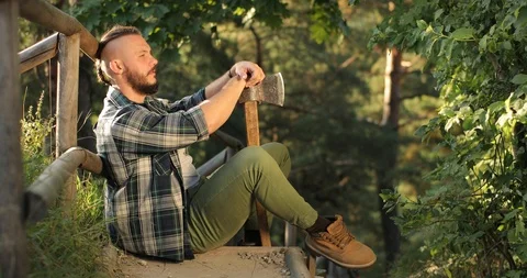 The young man feels sad. a man sits with his back against a wooden bridge and Stock Footage 126497975