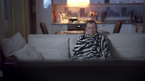 The young man fell ill in the evening sitting on the couch and watching TV Stock Footage 132319087
