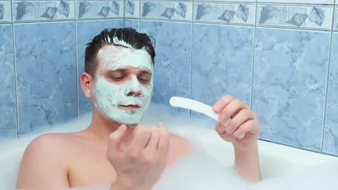 Young man is filing his nails sitting in bathroom with mask on face. Stock Footage 158384235