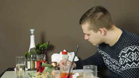 A young man fills up documents in a restaurant Video stock 84701847