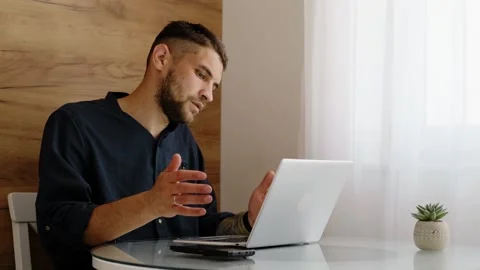 A young man finishes his work, closes the laptop, and stretches while sitting at Stock Footage 342541244