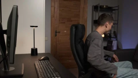Young man finishing computer work spinning on office chair at home authentic Stock Footage 316952044