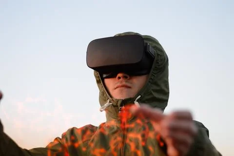 Young man, firefighter with VR headset and in a green protective jacket Stock Photos