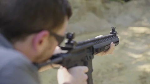 Young man fires an automatic asub machine gun an an outdoor range in the summer. Stock Footage 88164979