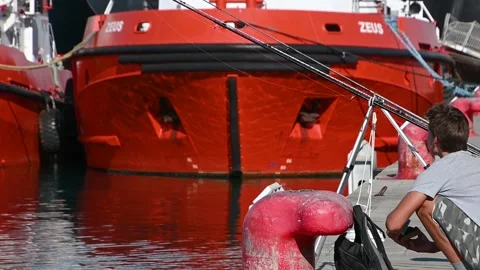 Young man fishing at harbor dock. View of tugboat Stock Footage 138897656
