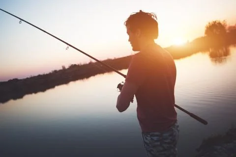 Young man fishing at pond and enjoying hobby Stock Photos