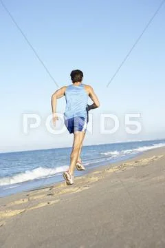 Young Man In Fitness Clothing Running Along Beach Stock Photos