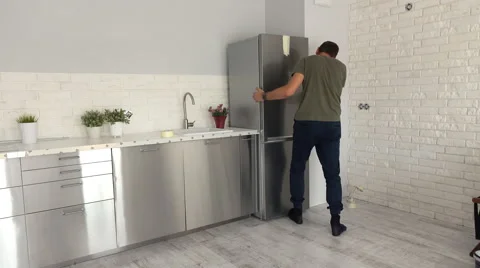 Young man fitting new fridge to furniture at his new home Stock Footage 67503137