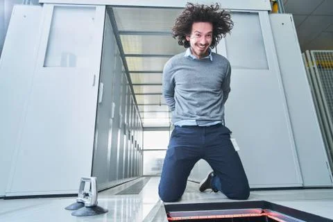 Young man fixing something in the floor hatch. Data center. Servers Stock Photos