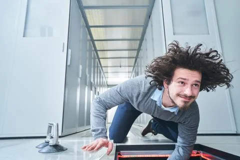 Young man fixing something in the floor hatch. Data center. Servers Stock Photos