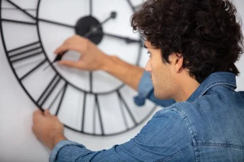Young man fixing a wall clock Stock Photos