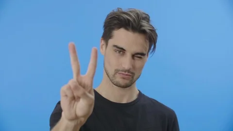 Young man flashes the peace sign while smiling 4K Stock Footage 88399705
