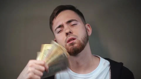 A young man flaunts a fan of dollar bills in front of his face Vidéo 147463541