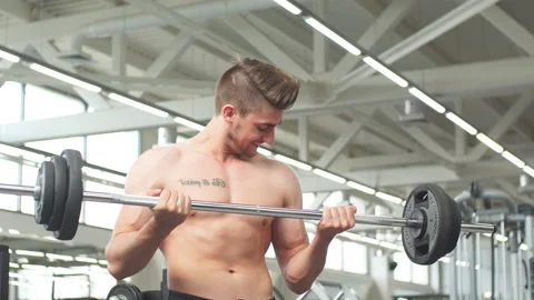 Young man flexing muscles with barbell in gym Stock Footage