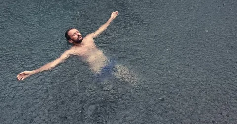 Young man floating on the back in the dark water of simming pool, ocean or lake Stock Footage 151548650
