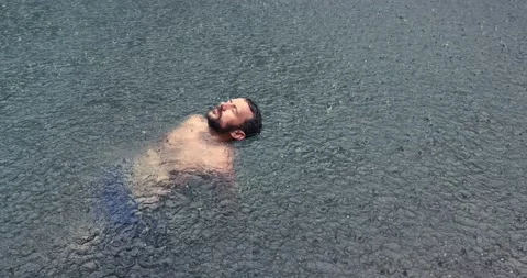 Young man floating on the back in the dark water of simming pool, ocean or lake Video stock 151549121