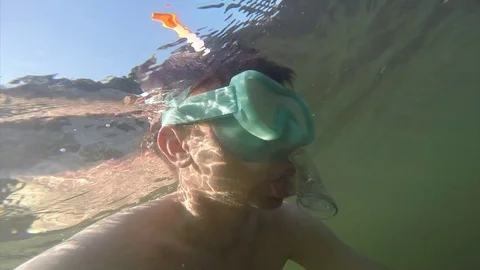 A young man floating under the water in a mask with a tube is floating in the Vídeos de archivo 82730210