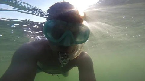 A young man floating under the water in a mask with a tube is floating in the Stock Footage 82730236