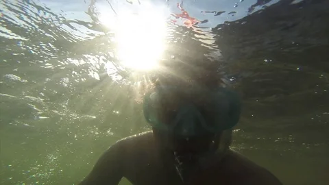 A young man floating under the water in a mask with a tube is floating in the Stock Footage 82730306