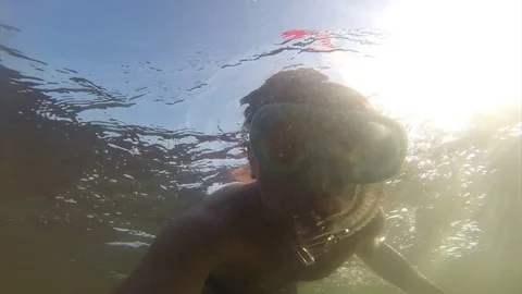 A young man floating under the water in a mask with a tube is floating in the Vídeos de archivo 82730354