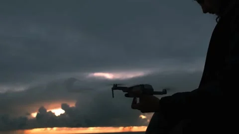 Young man flying a drone at sunset Stock Footage 242764998