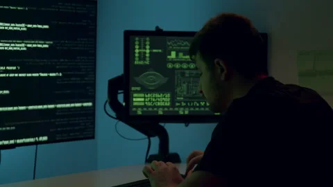 Young man focused on computer screens displaying coding and data analysis Stock Footage 313930502