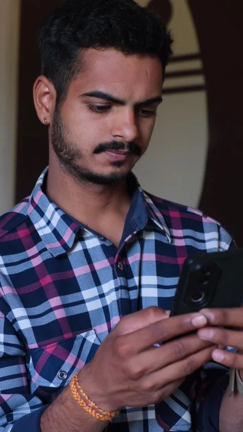 Young man focused on using his smartphone, scrolling through apps Vidéo 331354358