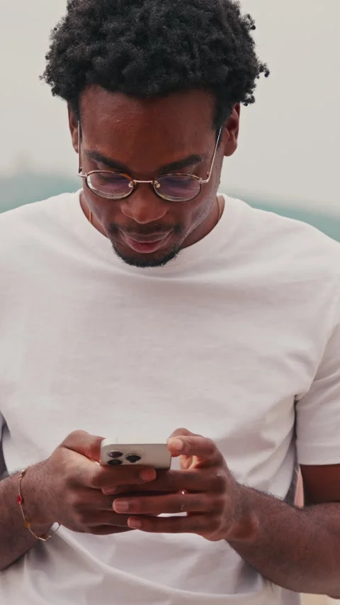 Young Man Focuses On His Mobile Phone Outdoors Stock Footage 329935637