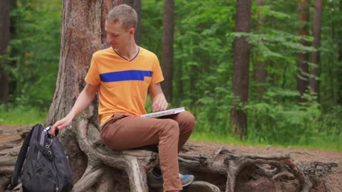 A young man in the forest reads a training book. Stock Footage 92313198