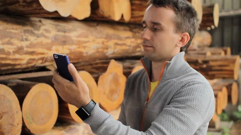 Young man forestry engineer touch phone in front of wood Stock Footage 65318663