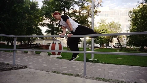 A young man free runner doing parkour and dancing over railing in the outdoors Video stock 117333700