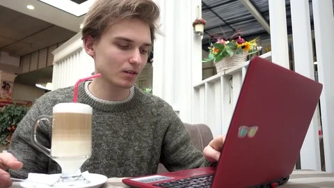 Young Man freelance outsource work Using Laptop In Cafe, drinking cocktail Stock Footage 71578489