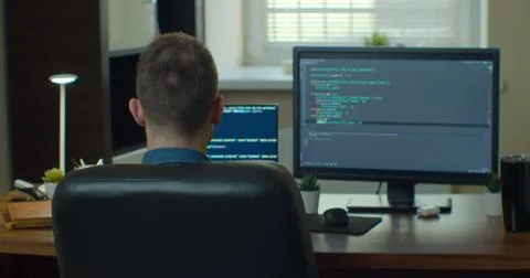 Young man freelancer coding html and programming on two screen Monitors Stock Photos