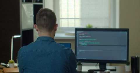 Young man freelancer coding html and programming on two screen Monitors Stock Photos