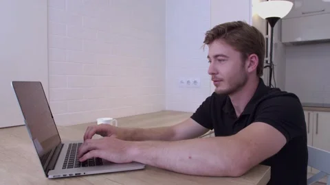 Young man freelancer using laptop, online working from home in the kitchen Stock Footage