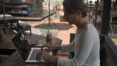 Young man freelancer working on a laptop computer in outdoor cafe 스톡 동영상 87954631