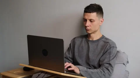 Young man freelancer working on laptop in bed at home, close-up, remote work Stock-Footage 314893324