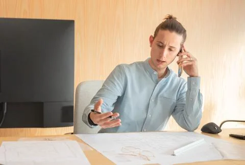 Young man frustrated while talking to clients in interior design office Stock Photos