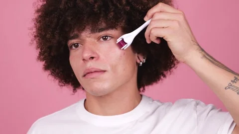 A young man with full, visible tattoos on his arm holds a derma roller to his Stock Footage 269362614