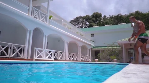 Young man funny posing falls into swimming pool Stock Footage 109099748