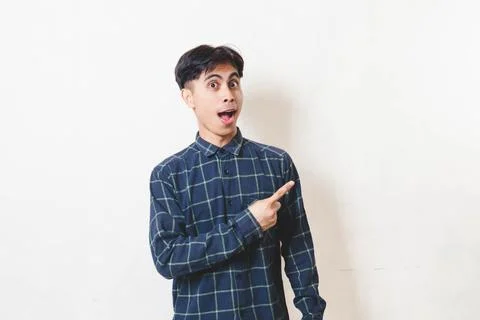Young man with a funny surprised expression pointing to the side, showing p.. Stock Photos