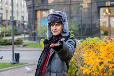 Young man in fur hat extending hand to invite woman on date. Romantic man m.. 스톡 사진