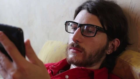 A young man with a gadget lying and having fun Video stock 82211338