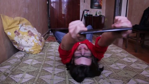 A young man with a gadget lying and having fun 動画素材 82211469