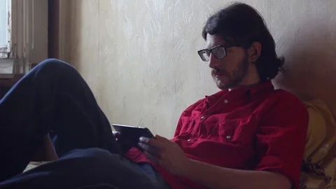 A young man with a gadget lying on sofa (tablet) Stock-Footage 81603630